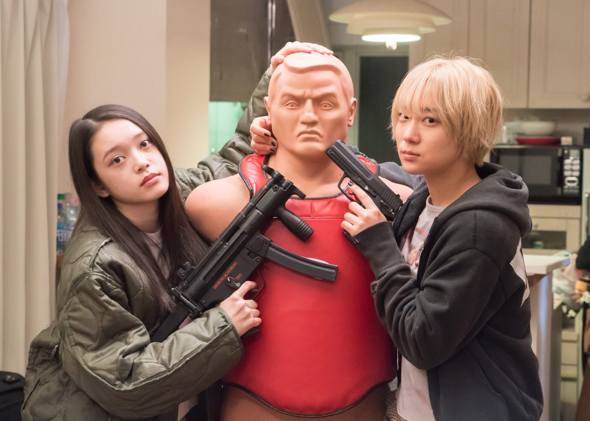 Chisato and Mahiro holding guns to a training dummy in Baby Assassins