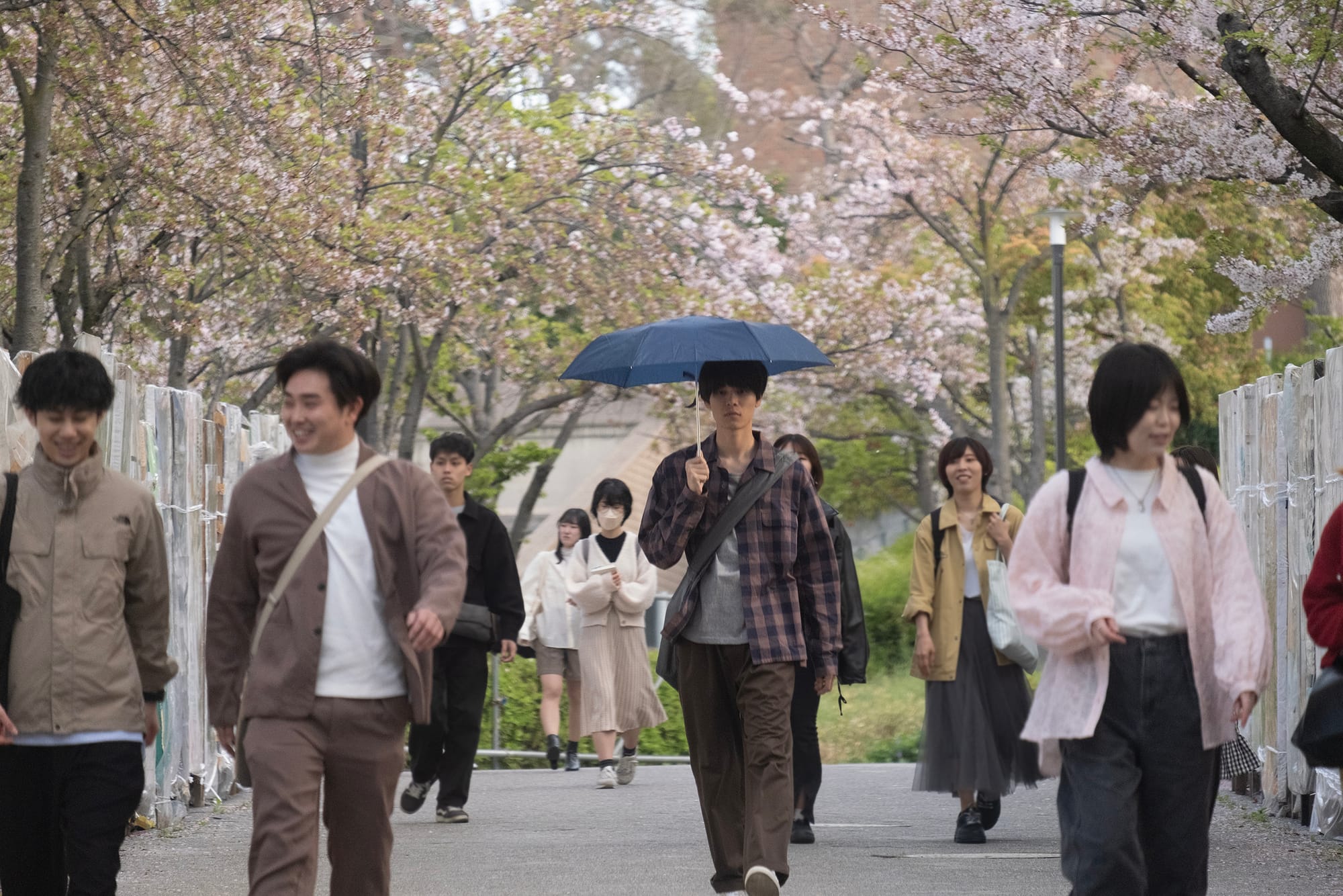 Toru Konishi walking amongst other people in She Taught Me Serendipity