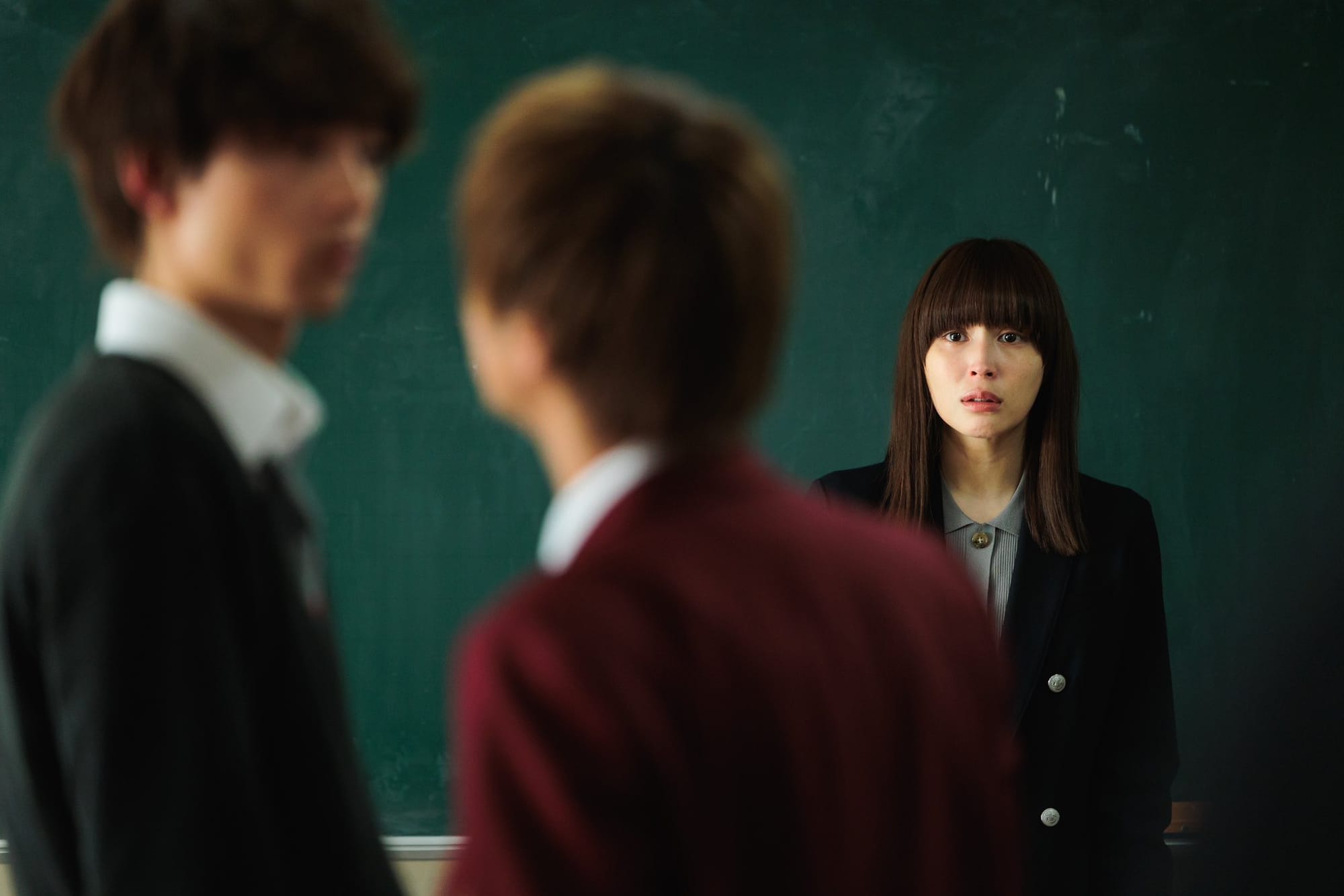 Shizuka looks on at two students in The Reluctant Preacher