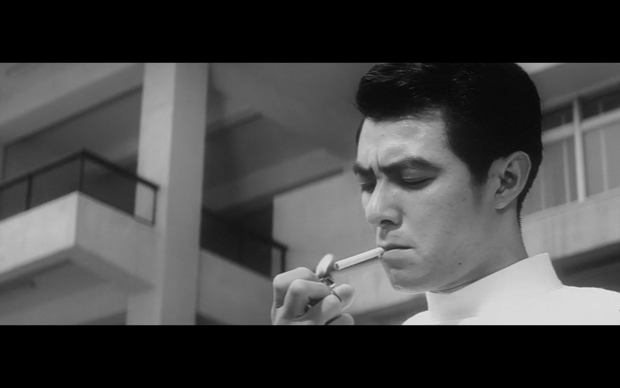 A man wearing a doctor's coat lights a cigarette.