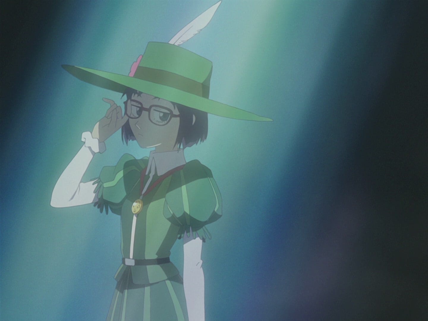 Ninamori, a girl wearing a green feathered hat and tunic, poses while wearing glasses. She is illuminated by a spotlight.